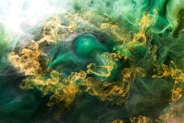 Golden sparkling abstract background, luxury green smoke, acrylic paint underwater explosion, cosmic swirling ink - Фото, изображение