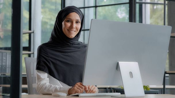 Confident successful elegant arab businesswoman typing on computer attractive muslim female in hijab professional worker experienced manager entrepreneur working in modern office posing in workplace - Foto, Bild