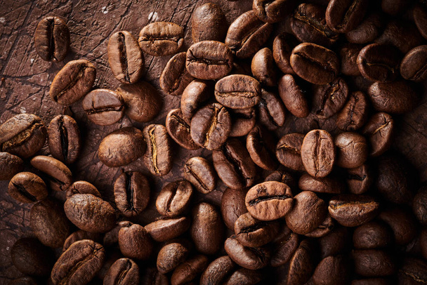 Roasted coffee beans isolated close up on brown grunge background - Photo, Image