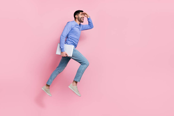 Full length photo of exited pretty arab guy dressed blue pullover jumping holding device empty space isolated pink color background. - Foto, immagini