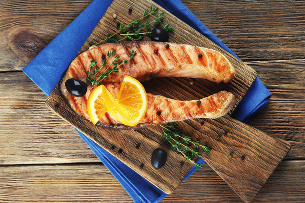 Grilled salmon  and orange slices on cutting board on wooden background - Fotografie, Obrázek