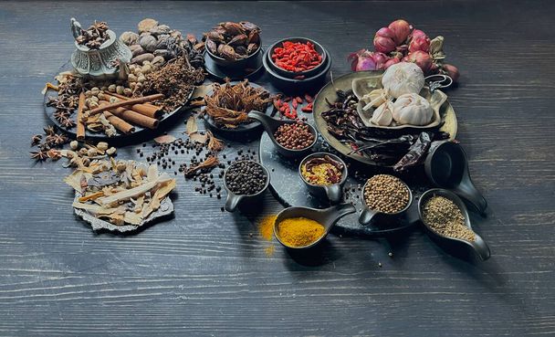 Assorted spices and herbs on a black table - Fotó, kép