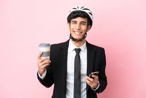 Argentinian businessman with bike helmen isoleted on pink background - Фото, изображение