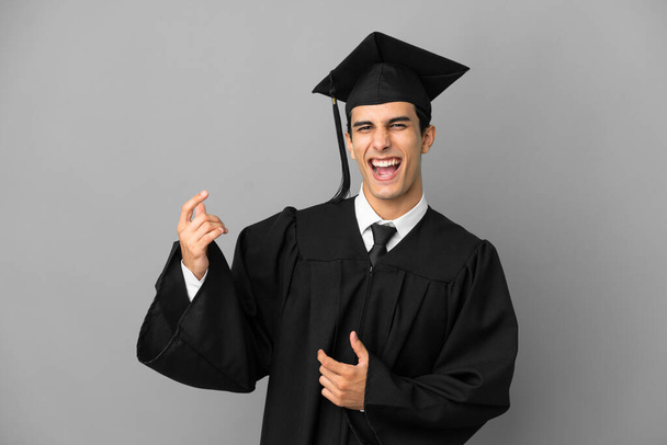 Young Argentinian university graduate isolated on grey background making guitar gesture - Foto, immagini