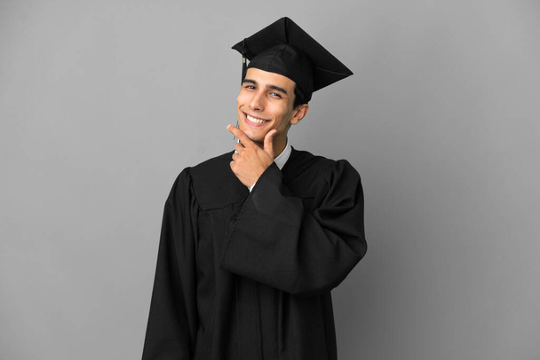 Молодой выпускник аргентинского университета на сером фоне улыбается - Фото, изображение