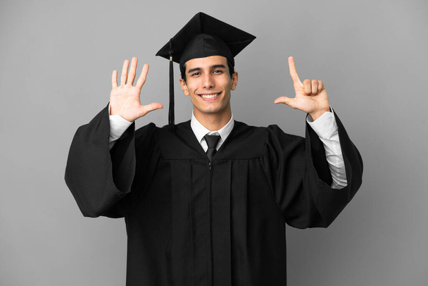 Joven graduada universitaria argentina aislada sobre fondo gris contando siete con dedos - Foto, imagen