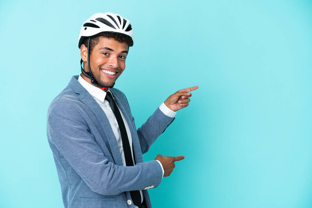 Bisiklet kasklı genç Brezilyalı adam mavi arka planda izole edilmiş. - Fotoğraf, Görsel