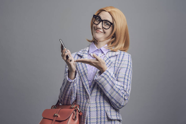 Happy satisfied woman looking at camera and showing her smartphone - Фото, изображение