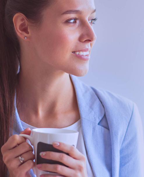 Attractive woman sitting at desk in office having takeaway coffee. - Фото, изображение