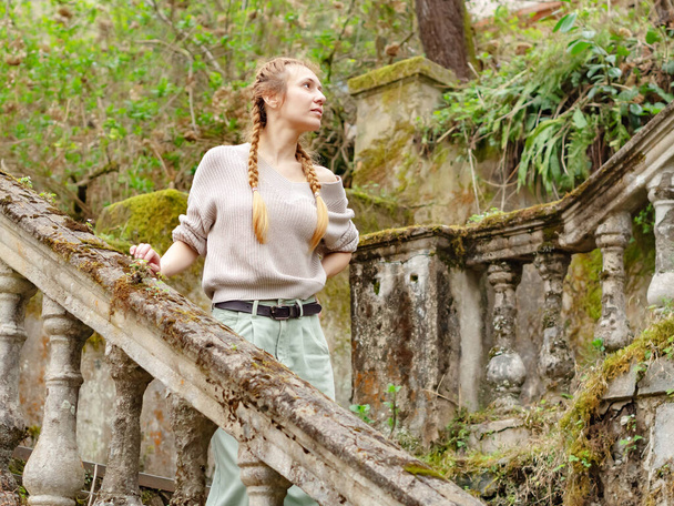 Donna che cammina sui gradini ricoperti di vegetazione di un parco abbandonato - Foto, immagini