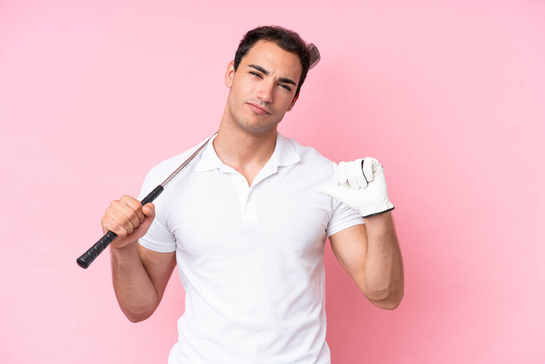 Νεαρός παίκτης του γκολφ άνθρωπος απομονωμένος σε ροζ φόντο υπερήφανος και αυτάρεσκος - Φωτογραφία, εικόνα