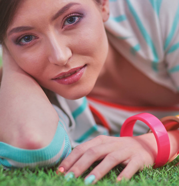 Beautiful young woman lying on the green grass. - Photo, image