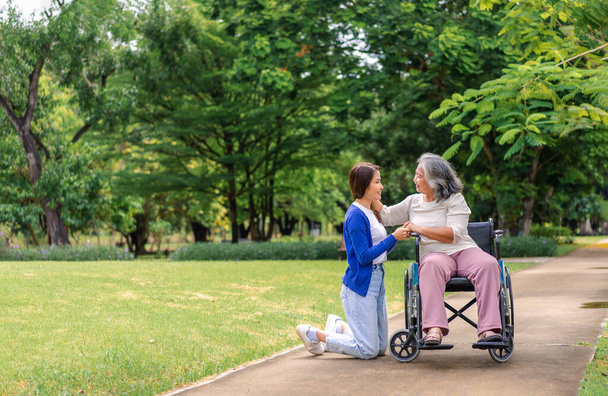Ázsiai gondozó vagy ápoló, aki a tolószékes beteget gondozza. Fogalma boldog nyugdíjba gondozás egy gondozó és megtakarítások és a vezető egészségbiztosítás, egy boldog család - Fotó, kép