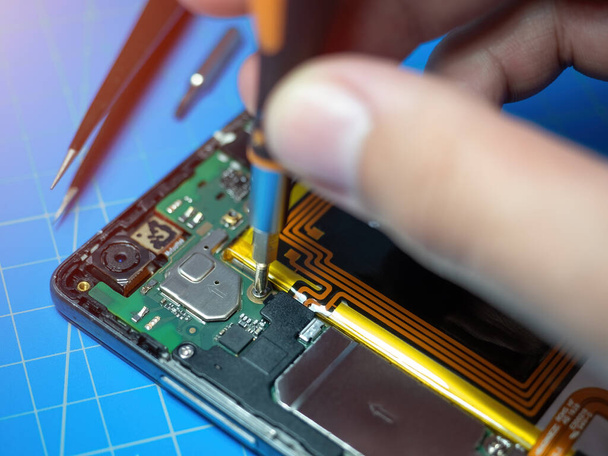 Akıllı telefon teknisyeni servis masasındaki akıllı telefonun ana kartını tamir ediyor. Elektronik donanım güncelleme ve onarım kavramı - Fotoğraf, Görsel