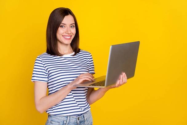 Photo of nice young woman hold laptop video online conference smiling dressed trendy striped look isolated on yellow color background. - Fotografie, Obrázek