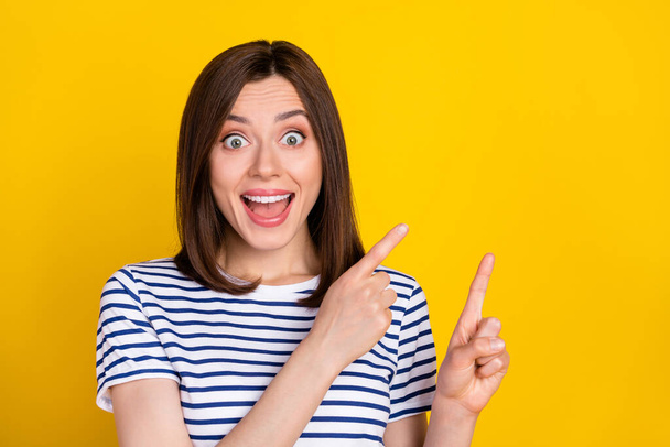 Photo portrait of lovely young lady excited point empty space impressed dressed trendy striped look isolated on yellow color background. - Foto, imagen