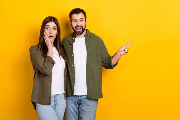 Portrait of attractive stunned cheerful couple hugging showing copy space new isolated over bright yellow color background. - Φωτογραφία, εικόνα