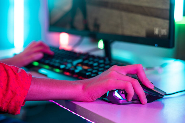 Close up shot of teenager kid hands using mouse while playing video game at neon light background - concept of entertainment, hobbies and technology - Zdjęcie, obraz
