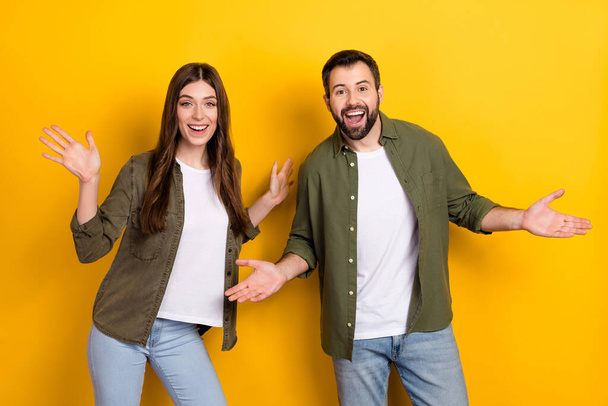 Photo of two overjoyed satisfied partners raise opened hands palms isolated on yellow color background. - Фото, изображение