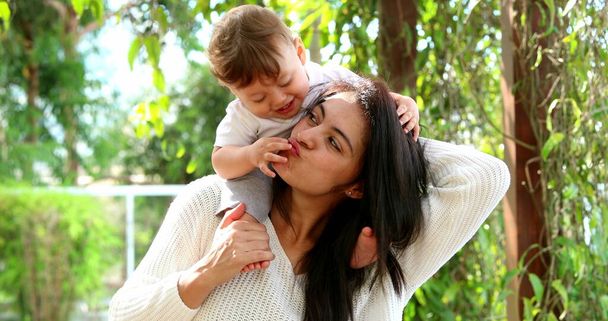 Cute mother and baby son caring and loving relationship. Casual infant sitting on mom shoulders - Zdjęcie, obraz
