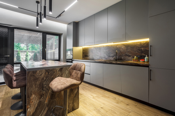 Moderno apartamento de lujo con una distribución libre en un estilo loft en colores grises y oscuros. Elegante cocina con una encimera de mármol de la isla - Foto, imagen