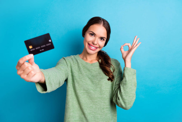 Portrait of attractive cheerful person hand hold showing debit card okey symbol feedback isolated on blue color background. - Фото, изображение