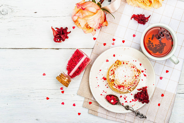 The concept of romantic tea. French Shu cake, hibiscus tea, bouquet of roses, festive decor. Valentine's Day concept, Women's Day March 8, Wedding. White boards background - 写真・画像