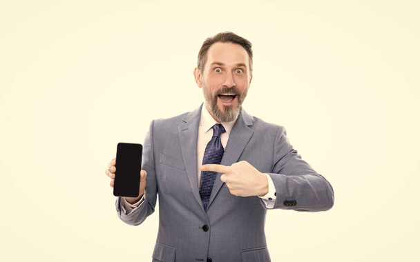 здивований бризкоподібний бос у костюмі, що представляє сучасний мобільний телефон ізольований на білому копіювальному просторі, просування
. - Фото, зображення