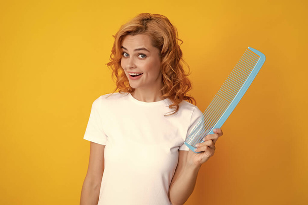 Redhead woman with a comb, isolated on yellow background - Photo, Image