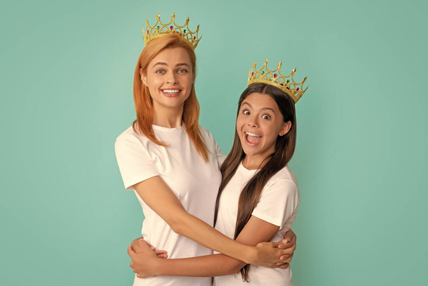 Happy woman and girl child in crowns hug smiling blue background, mother. - Photo, Image