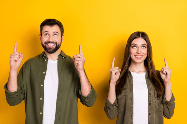 Portrait of cheerful nice partners look interested direct fingers up empty space isolated on yellow color background. - Foto, immagini