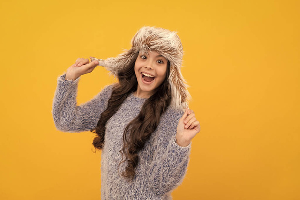 asombrado chica adolescente usar sombrero de oreja sobre fondo amarillo, mantener caliente. - Foto, imagen