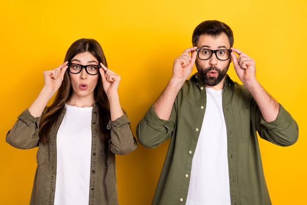 Portrait of attractive stunned funny couple touching specs reaction omg isolated over bright yellow color background. - Foto, Imagem
