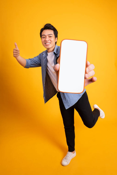 Asiatico giovane uomo posa su uno sfondo giallo - Foto, immagini