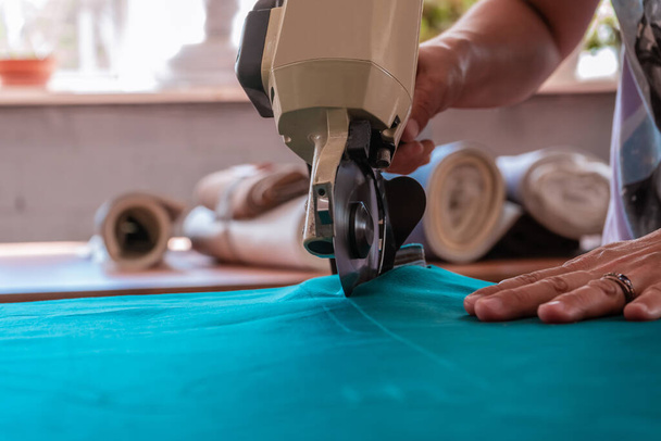 The cutter cuts the fabric with a disc knife in a sewing workshop - Fotografie, Obrázek