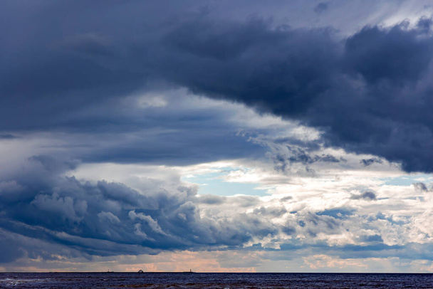 Dramatic stormy dark cloudy sky over Baltic sea just before a sea storm in Riga, Latvia. Nature environment concept. - 写真・画像