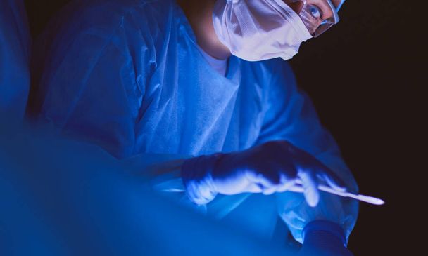 Doctors team in surgery in a dark background - Valokuva, kuva