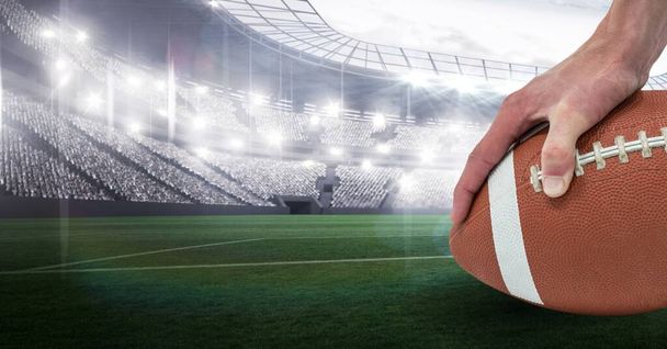 Composition of male rugby player holding rugby ball over sports stadium. sport and competition concept digitally generated image. - Valokuva, kuva