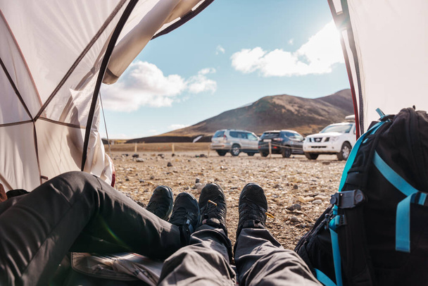 Nogi pary podróżników relaksujących się w namiocie na pustkowiu na kempingu w lecie w Islandzie - Zdjęcie, obraz