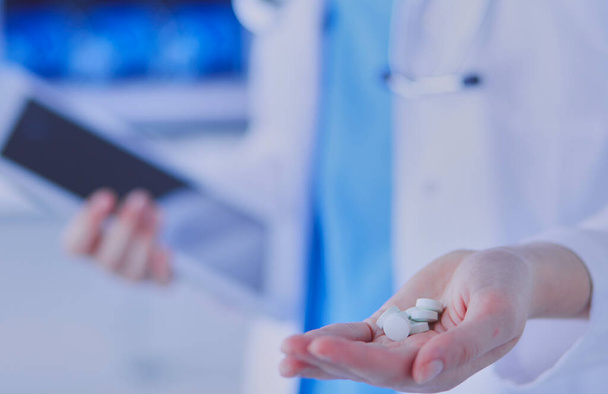 Close-up shot of doctors hands holding pills and tablet at clinic - Fotó, kép