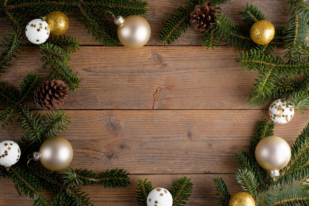 Cornice decorazione abete di Natale su sfondo in legno rustico. Fondo natalizio con rami di abete, palline d'oro, coni, spazio piatto per posare e copiare, elemento per il design - Foto, immagini