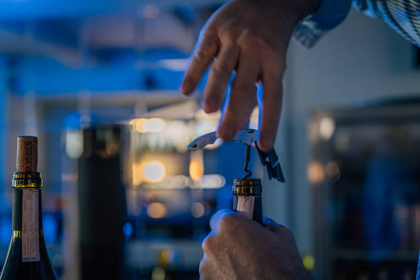 Hands of a sommelier opening a bottle of wine with a corkscrew - 写真・画像