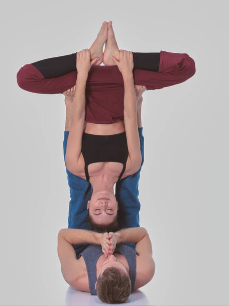 Young athletic couple practicing acroyoga. Balancing in pair - 写真・画像