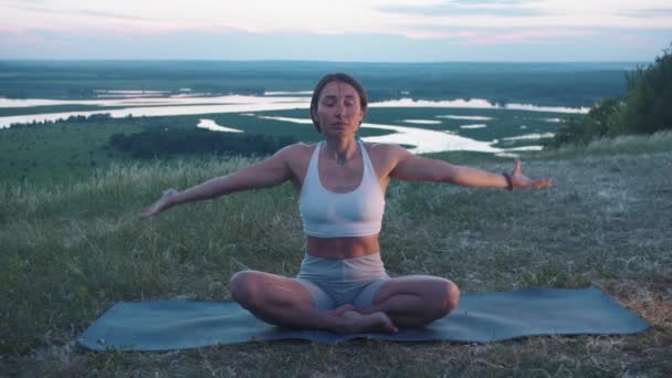 Akşamüstü tepede meditasyon yapan zayıf yetişkin bir kadın. Orta çekim - Video, Çekim