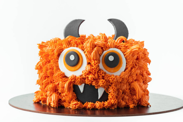 Monster téma dort na bílém pozadí. Halloween dort s oranžovou nadýchaný smetanový sýr poleva izolované na bílém - Fotografie, Obrázek