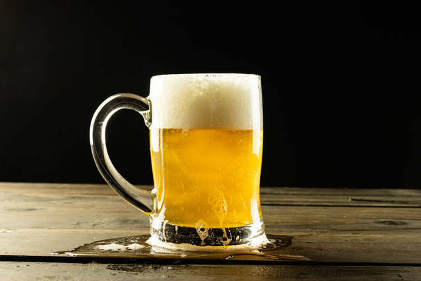 Image of glass tankard full of foamy beer on wooden table, with copy space. Drinking alcohol, refreshment and lager day celebration concept. - Фото, изображение