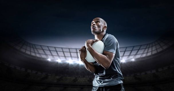 Composition of male rugby player holding rugby ball over sports stadium. sport and competition concept digitally generated image. - Foto, imagen