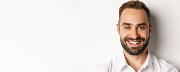 Headshot of handsome bearded man smiling, standing against white background. - Foto, Imagem