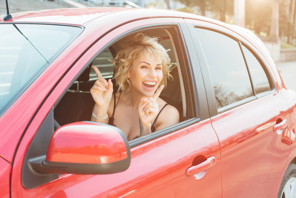 Attractive blonde in a car showing keys. - Foto, afbeelding