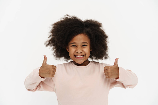 Black preteen girl with curly hair smiling and showing thumbs up isolated over white background - Foto, imagen